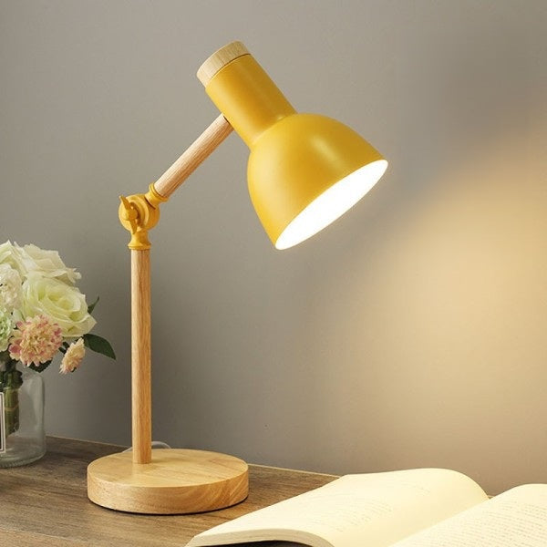 Lampe de chevet de couleur bois, avec un abat-jour jaune. L'articulation du bras est jaune et il y a une vis de serrage jaune, pour immobiliser l'inclinaison de la lampe.