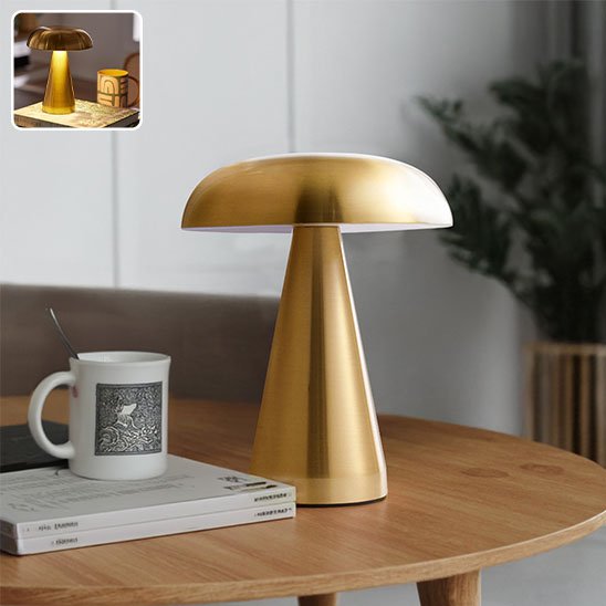 Lampe champignon de couleur or déposée sur une table à café avec une tasse par dessus un livre.