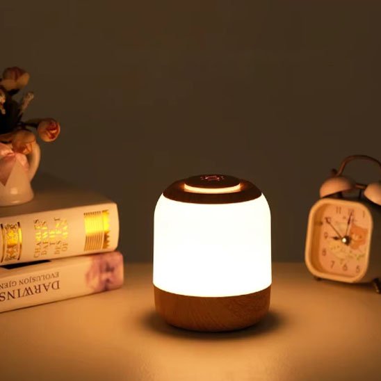 Lampe de chevet tactile | LumiTouch-Reactive posée sur une table de chevet à côté de deux volume et un réveille matin