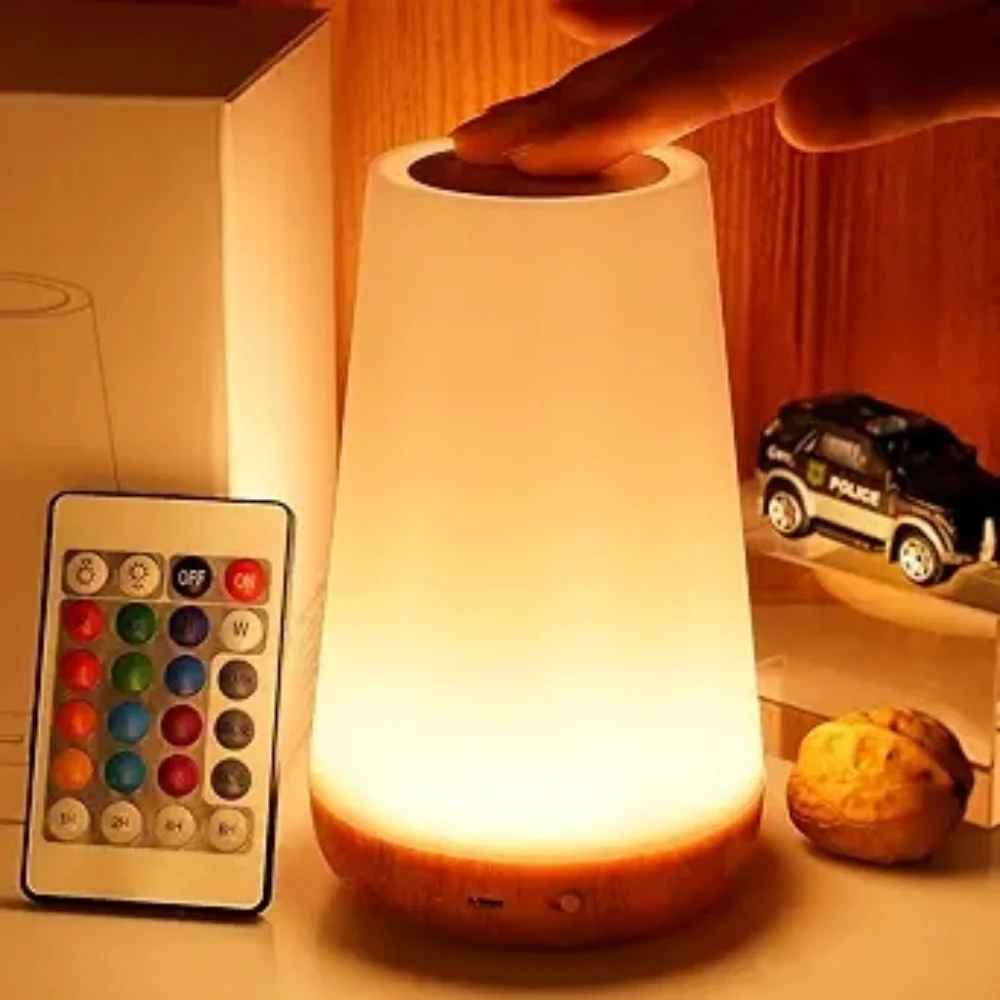 On voit des doigt qui touche le dessus pour l'allumer la Lampe de chevet tactile | LumiTouch et la télécommande posée à côté.