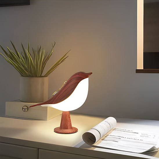 On voit une revue ouverte sur le dessus d'un classeur sur lequel la Lampe de chevet tactile | NatureBird de couleur Noyer appelé rouge est allumée.