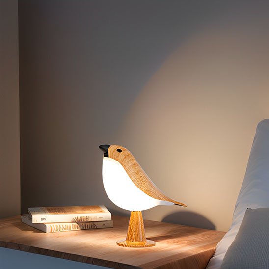 On voit la Lampe de chevet tactile | NatureBird allumée près de deux livres posés sur la même table.
