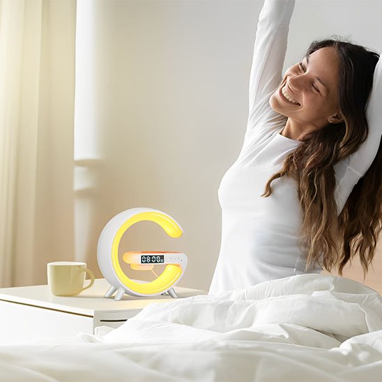 Lampe de chevet design | Réveil LED Couleur blanche. Simulation des couleur de l'aube au réveil. Une femme s'étire, toute souriante dans son lit.