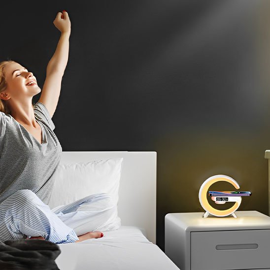 Lampe de chevet design | Réveil LED Couleur blanche. Simulation des couleur de l'aube au réveil. Une femme s'étire, toute souriante dans son lit et la lampe est au couleurs du soleil levant.