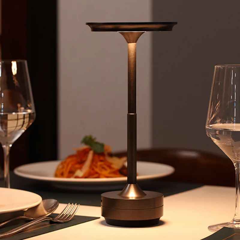 Lampe MoedernTouch de couleur anthracite posée sur une table. On voit deux couvercles et on peut voir une des assiettes avec de la nourriture et deux verres de vin blanc