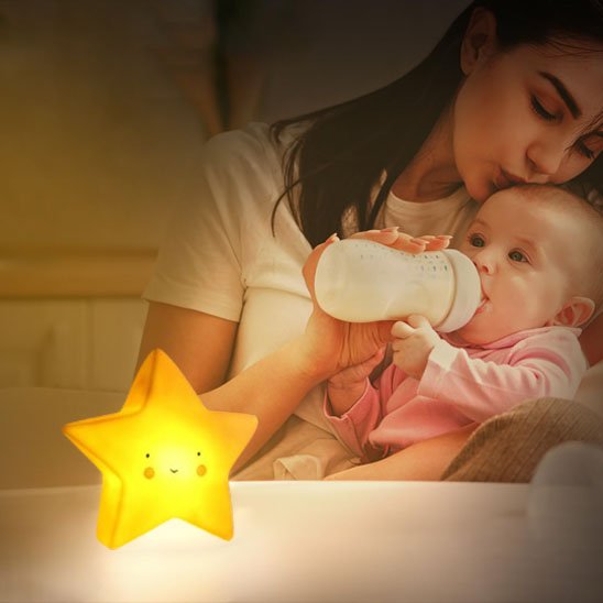 Une veilleuse bébé | Étoile Douce Nuit de couleur Jaune éclaire une maman qui donne le biberon à son bébé