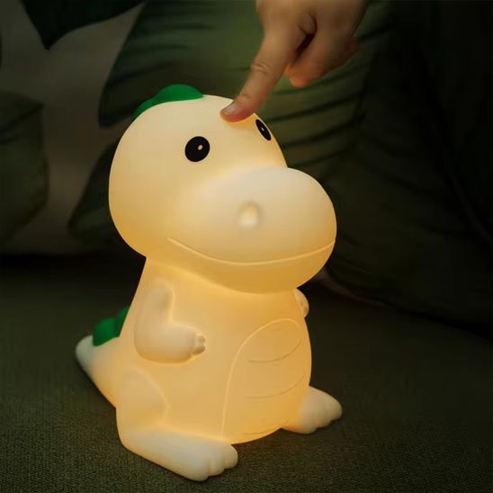Un doigt d'enfant presse sur la tête de la veilleuse bébé | dinosaure DinoNuit