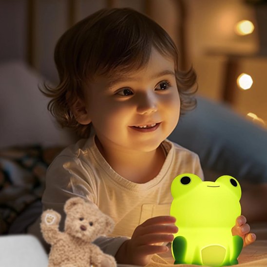 Une fillette tient la veilleuse bébé | Grenouille Lumina dans ses mains