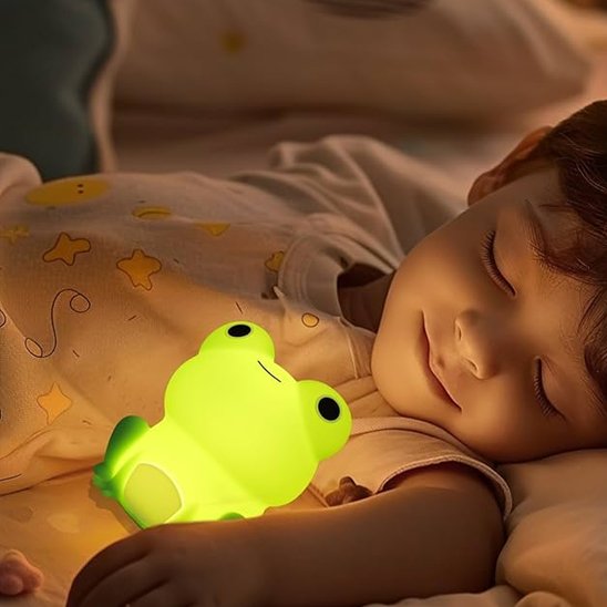 Un jeune enfant dort avec la veilleuse bébé | Grenouille Lumina sous son bras