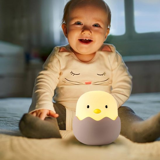 Un jeune enfant est assis avec la veilleuse enfant | Poussin Dodo posé au sol entre ses jambes