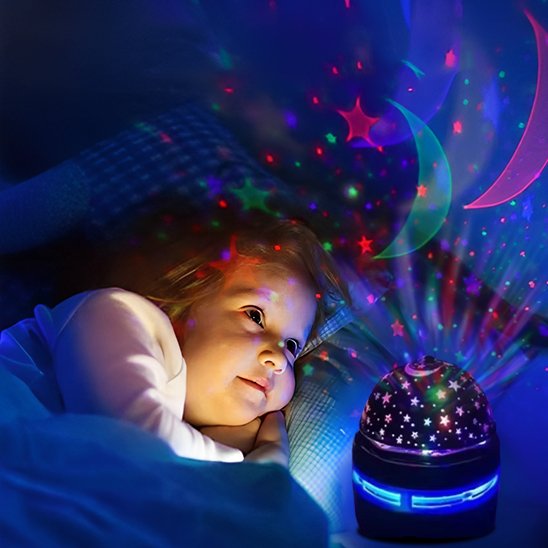 Un enfant admire les étoiles colorées que la veilleuse projection plafond | CielEtoileMagique fait tournoyer dans sa chambre