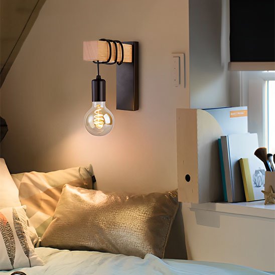 L'applique mural | Design Scandinave noire installée sur un mur au-dessus d'un lit qui est situé à proximité du rebord d'une fenêtre sur laquelle des livres et des objets sont ranger