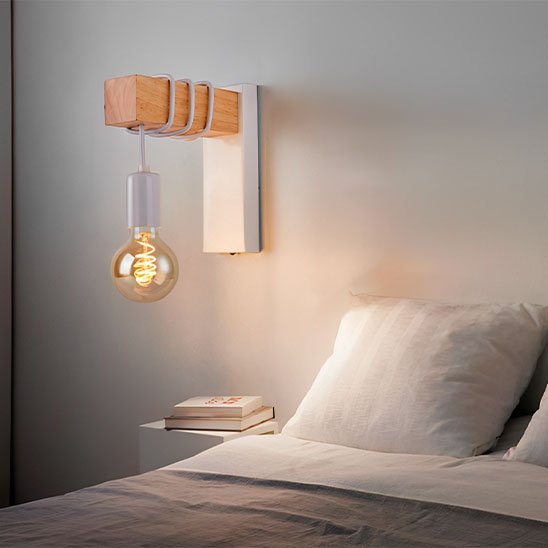 L'applique mural | Design Scandinave blanche installée au-dessus d'une petite table de chevet sur laquelle on voit deux livres.