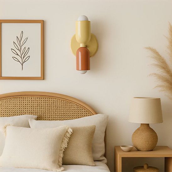 On voit une applique murale chambre | Design Ajustable l'abat-jour du haut est beige, celui du bas est prune et le châssis beige. L'applique est installé au-dessus d'une tête de lit.