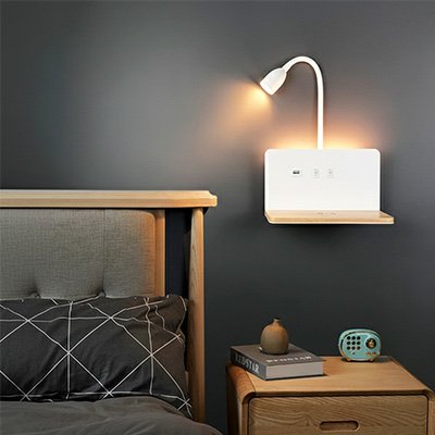 On voit l'applique murale pour chambre ! DesignFunction de couleur blanche avec sa tablette de couleur HĂȘtre, installĂ©e sur un mur au-dessus de la table de chevet. Sa lumiĂšre est tournĂ©e vers le lit.