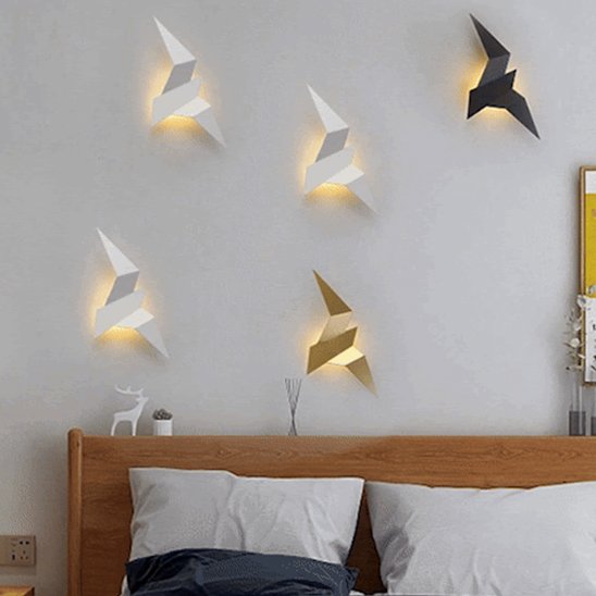 On voit une envolĂ©e de cinq appliques murales chambre | Design Cosy, une noire, une or et 3 blanches. Elles sont InstallĂ©es au mur au-dessus d'une tĂȘte de lit en bois.