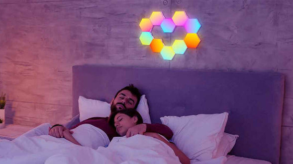 On voit un ensemble de 10 appliques murales intĂ©rieur | DesignHexa formant un coeur installĂ© sur le mur au-dessus d'une tĂȘte de lit. Dans ce lit un couple dort paisiblement.