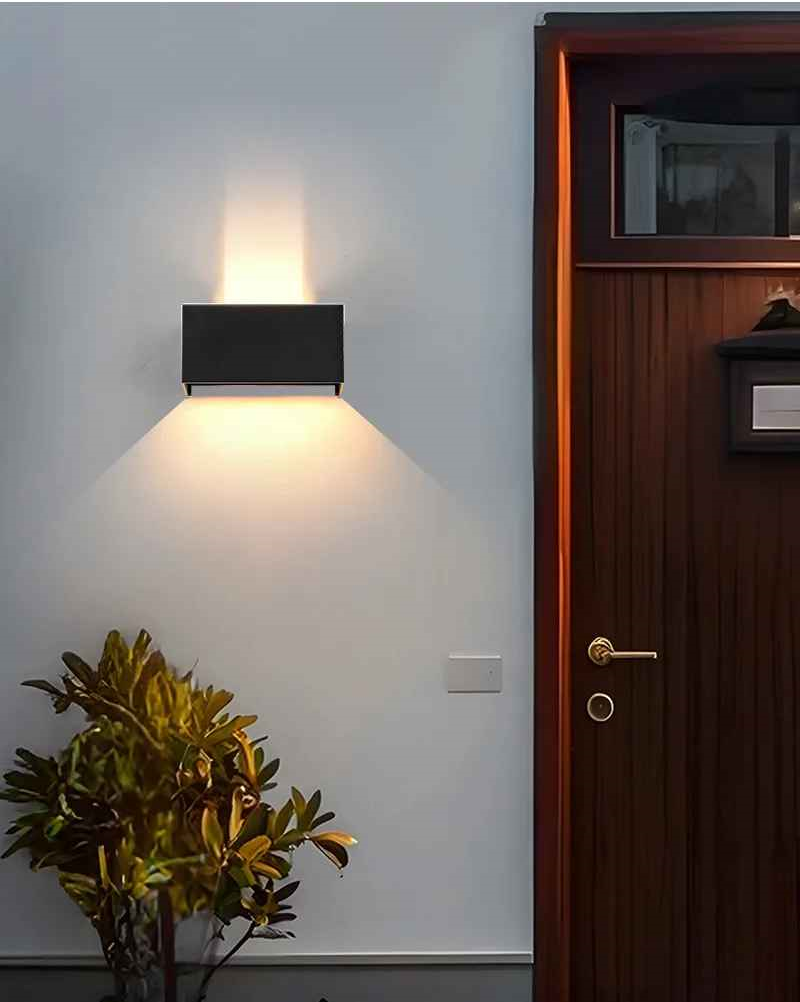 On voit l'applique murale | Luminescence 24 watt noire installée sur un mur près d'une porte en bois avec un ajustement d'éclairage étroit en haut et 120 degrés vers le bas.