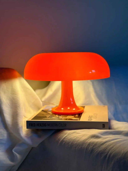 Lampe Champignon | Vintage posée sur un livre qui chevauche l'oreiller et le bras d'un fauteuil à côté du lit