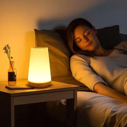 On voit une femme endormie avec la Lampe de chevet tactile | LumiTouch cencore allumée sur sa table de chevet.