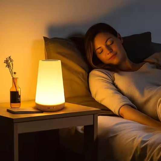 On voit une femme endormie avec la Lampe de chevet tactile | LumiTouch cencore allumée sur sa table de chevet.