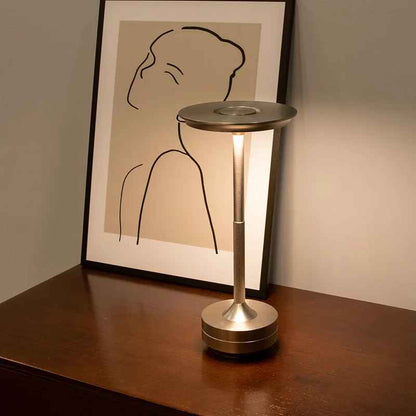 Lampe MoedernTouch de couleur or posée sur un meuble sur lequel un cadre est présent appuyé sur un mur