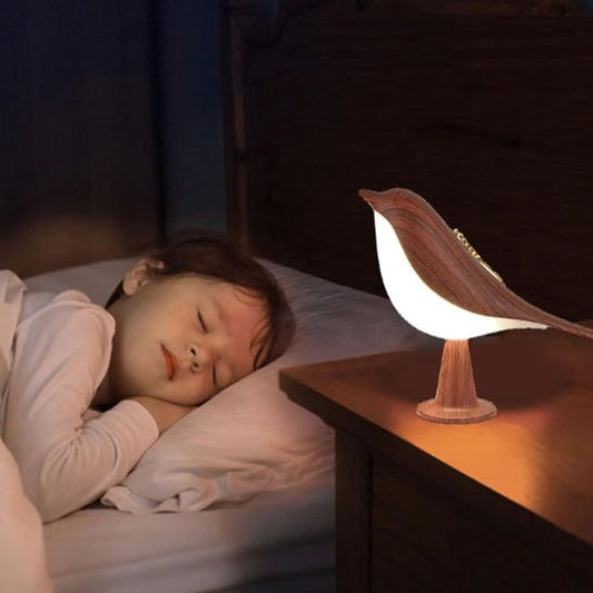 On voit un enfant endormi avec la Lampe de chevet tactile | NatureBird de couleur Noyer appelé rouge,  encore allumée sur sa table de chevet.