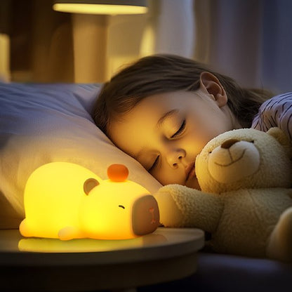 Une fillette est endormie éclairée par la veilleuse bébé | CochonLumineux Kapybara posée sur sa table de chevet