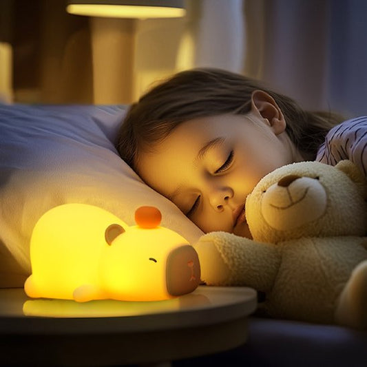 Une fillette est endormie éclairée par la veilleuse bébé | CochonLumineux Kapybara posée sur sa table de chevet