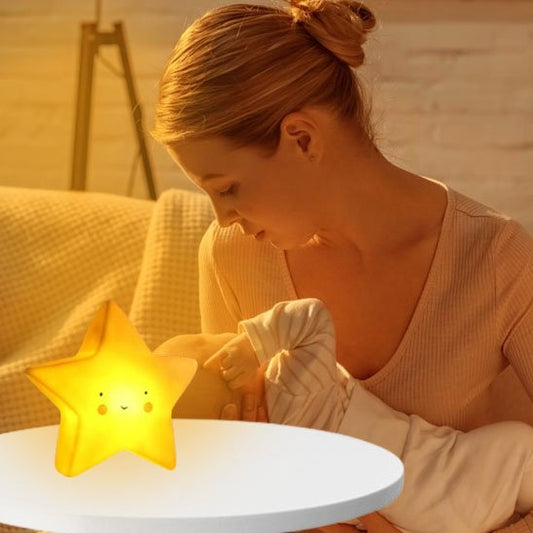Une veilleuse bébé | Étoile Douce Nuit de couleur Jaune posée sur une table à café éclaire une maman qui tient son bébé