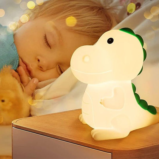 Un jeune enfant dort avec la veilleuse bébé | dinosaure DinoNuit posée sur sa table de chevet