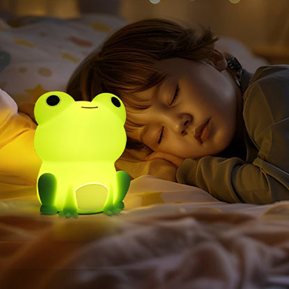 Un enfant dort avec la veilleuse bébé | Grenouille Lumina posée sur son lit