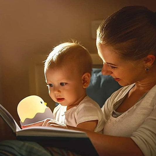 Un maman lit une histoire à son jeune enfant fasciné. L'enfant tient la veilleuse enfant  | Poussin Dodo