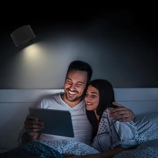 On voit un couple collé au lit qui regarde un document éclairé par l'applique murale chambre  | Design Luminescence.