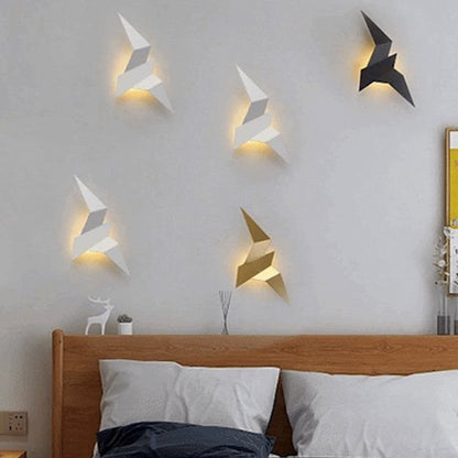 On voit une envolée de cinq appliques murales chambre | Design Cosy, une noire, une or et 3 blanches. Elles sont Installées au mur au-dessus d'une tête de lit en bois.