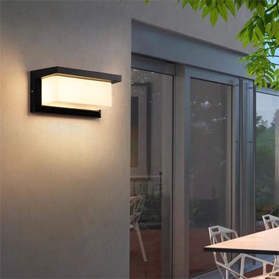 On voit l'applique murale pour extérieur | Robusta installée sur un mur près d'une porte vitrée donnant accès à la terrasse.