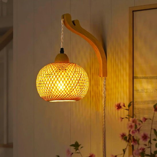 On voit une applique murale rotin | Artisanale fixé au mur au dessus d'une plante fleurir