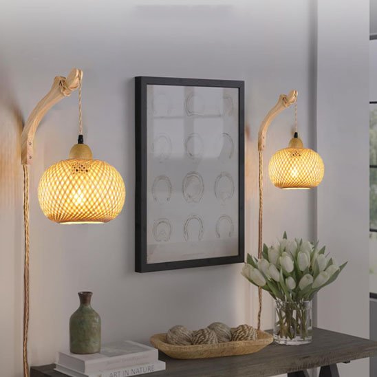 Un table de hall d'entrée sur laquelle sont posés des objets décoratif et deux volume. Au dessus un care est fixé au mur. De chaque côté de ce cadre, il y a une applique murale rotin ! Artisanale d'installée.